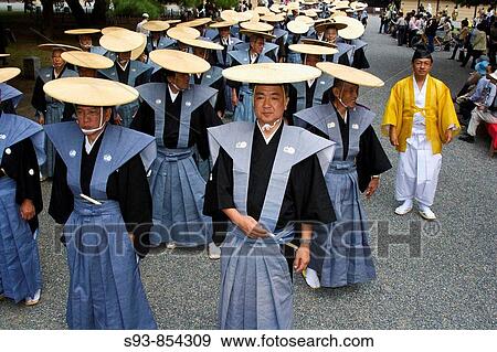Stock Photo - Japanese men dressed up in traditional costumes with flat circular hats walk in the Jidai Matsuri Festival of Ages in Kyoto. Fotosearch
