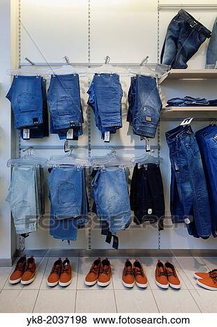 Stock Photo - Jeans, trousers and shoes in retail shop interior. Store display with rack, shelf.. Fotosearch