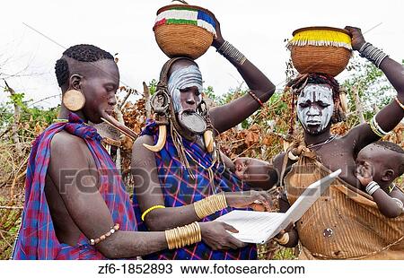 Jinka Ethiopia Africa village Lower Omo Valley Mago National Park wild tribe Mursi women with clay pots in their lips working on modern computer email in tribal portrait with paint on faces and traditional culture 15 View Large Photo Image Stock Image - Jinka Ethiopia Africa village Lower Omo Valley Mago National Park wild tribe Mursi women with clay pots in their lips working on modern computer email in tribal portrait with paint on faces and traditional culture 15. Fotosearch