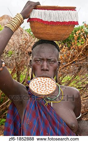 Stock Photo - Jinka Ethiopia Africa village Lower Omo Valley Mago National Park wild tribe Mursi woman with clay pot in her lip in tribal portrait with paint on faces and traditional culture 15. Fotosearch