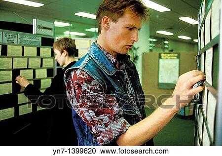 Stock Image - Job hunters checking through the list at social security. Fotosearch