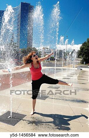 Picture - jumping girl having fun, diplomatic part of Geneva, fountains in front of Palace of Nations, building of WIPO in the background, Switzerland. Fotosearch