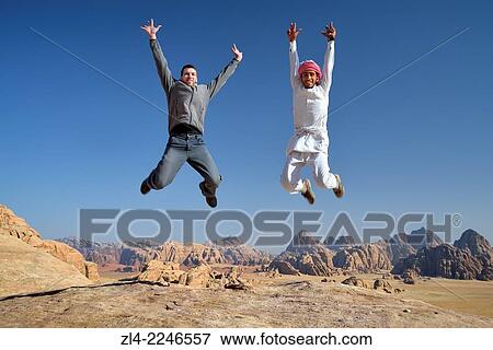 Jumping shot of a Bedouin and a tourist at the mount Jebel Burdah. Jordan, Wadi Rum desert, protected area inscribed on UNESCO World Heritage list. Model Released. View Large Photo Image Stock Photo - Jumping shot of a Bedouin and a tourist at the mount Jebel Burdah. Jordan, Wadi Rum desert, protected area inscribed on UNESCO World Heritage list. Model Released.. Fotosearch