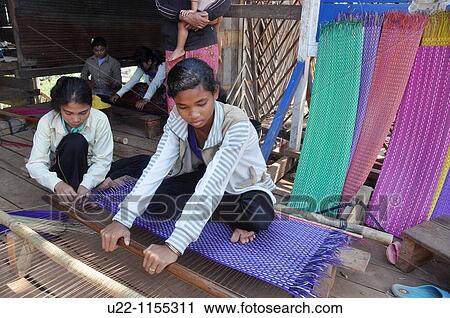 Stock Image - Kampong Khleang (Cambodia): village girls working at the loom. Fotosearch