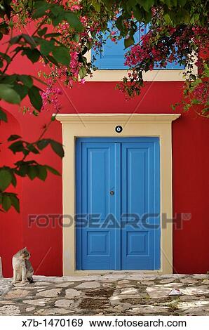 Stock Photo - Kastellorizo Dodecanese Islands Greece Cat sat outside a brightly coloured house. Fotosearch
