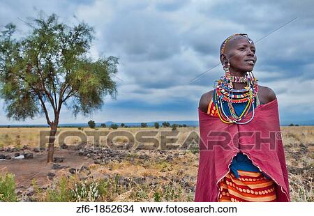 Kenya Africa Amboseli Maasai tribe village Masai woman in red costume dress and beads and tree in remote area of Amboseli National Park safari 1 View Large Photo Image Picture - Kenya Africa Amboseli Maasai tribe village Masai woman in red costume dress and beads and tree in remote area of Amboseli National Park safari 1. Fotosearch