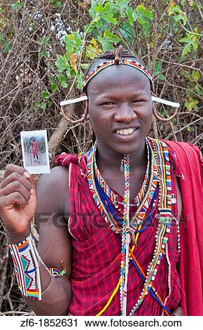 Kenya Africa Amboseli Maasai tribe village Masai man in red costume dress and beads holding Fuji Polaroid in remote area of Amboseli National Park safari 1 View Large Photo Image Stock Image - Kenya Africa Amboseli Maasai tribe village Masai man in red costume dress and beads holding Fuji Polaroid in remote area of Amboseli National Park safari 1. Fotosearch