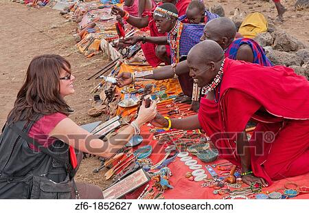 Kenya Africa Amboseli Maasai tribe village Masai in red costumes dress buying souvenirs with woman tourist in remote area of Amboseli National Park safari 1 View Large Photo Image Stock Photo - Kenya Africa Amboseli Maasai tribe village Masai in red costumes dress buying souvenirs with woman tourist in remote area of Amboseli National Park safari 1. Fotosearch