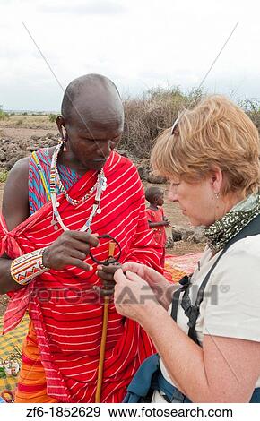 Kenya Africa Amboseli Maasai tribe village Masai man in red costumes dress buying souvenirs with woman tourist in remote area of Amboseli National Park safari 1 View Large Photo Image Stock Photo - Kenya Africa Amboseli Maasai tribe village Masai man in red costumes dress buying souvenirs with woman tourist in remote area of Amboseli National Park safari 1. Fotosearch