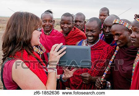 Kenya Africa Amboseli Maasai tribe village Masai group of men in red costume dress looking at Digital Tablet movie from tourist fun in remote area of Amboseli National Park safari 1 View Large Photo Image Stock Photograph - Kenya Africa Amboseli Maasai tribe village Masai group of men in red costume dress looking at Digital Tablet movie from tourist fun in remote area of Amboseli National Park safari 1. Fotosearch