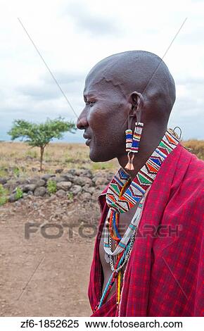 Kenya Africa Amboseli Maasai tribe village Masai man in red costume dress and beads close up of jewelry in remote area of Amboseli National Park safari 1 View Large Photo Image Stock Photography - Kenya Africa Amboseli Maasai tribe village Masai man in red costume dress and beads close up of jewelry in remote area of Amboseli National Park safari 1. Fotosearch