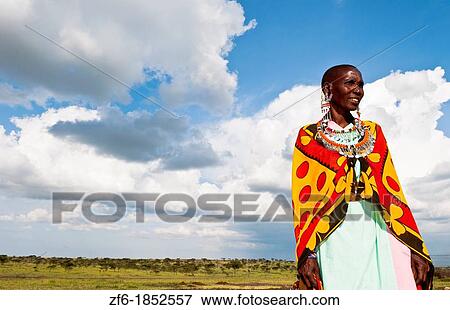 Stock Photo - Kenya Masai Mara reserve with Masai woman in colorful dress with blue sky in Masai Mara National Park in reserve 10. Fotosearch