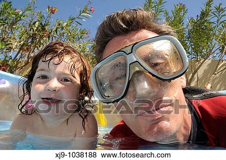 Stock Photo - Kids and dads who do swim in the pool in the garden. Fotosearch