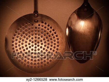 Stock Photo - Kitchen utensils hanging on wall Spoon and draining spoon. Fotosearch
