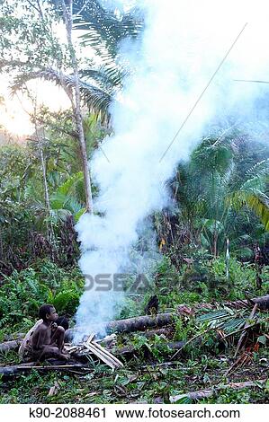 Kombai boy sitting at a fireplace, Papua, Indonesia, Southeast Asia. View Large Photo Image Stock Image - Kombai boy sitting at a fireplace, Papua, Indonesia, Southeast Asia.. Fotosearch
