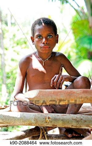 Picture - Kombai boy sitting in front of a wooden house, Papua, Indonesia, Southeast Asia.. Fotosearch