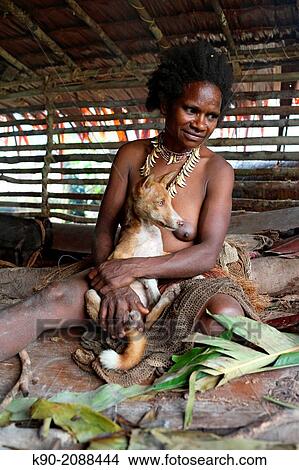 Picture - Kombai woman sitting with necklace made of dog teeth and holding a dog, Papua, Indonesia, Southeast Asia.. Fotosearch