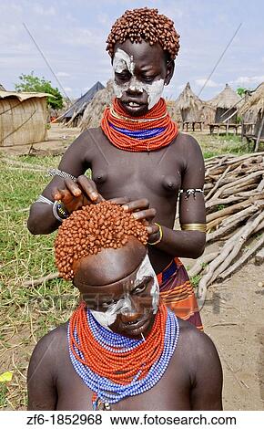 Stock Photo - Korcho Ethiopia Africa village Lower Omo Valley Karo tribe with painted faces fixing red hair curls 25. Fotosearch