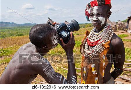 Korcho Ethiopia Africa village Lower Omo Valley Karo tribe with painted faces with boy using modern camera taking photos 25 View Large Photo Image Stock Photograph - Korcho Ethiopia Africa village Lower Omo Valley Karo tribe with painted faces with boy using modern camera taking photos 25. Fotosearch