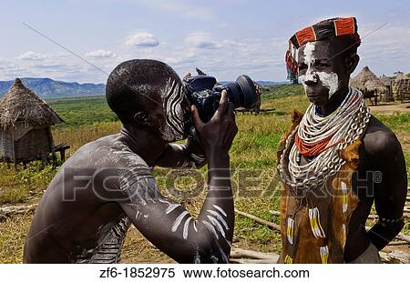 Korcho Ethiopia Africa village Lower Omo Valley Karo tribe with painted faces with boy using modern camera taking photos 25 View Large Photo Image Stock Photography - Korcho Ethiopia Africa village Lower Omo Valley Karo tribe with painted faces with boy using modern camera taking photos 25. Fotosearch