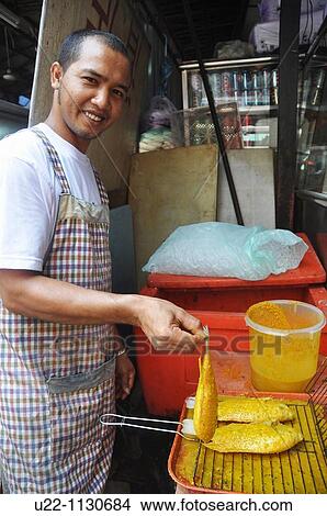 Kuala Lumpur (Malaysia): a man grilling some fish at a stall by Chinatown View Large Photo Image Picture - Kuala Lumpur (Malaysia): a man grilling some fish at a stall by Chinatown. Fotosearch