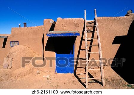 Stock Image - Ladder and adobe house with blue door, South House (World Heritage Site), Taos Pueblo, New Mexico USA.. Fotosearch