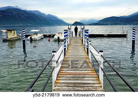 Lake Como, single man on the platform in Menaggio looking in Bellagio direktion, Varenna on left in background, Como province, Lombardy, Italy. View Large Photo Image Stock Photo - Lake Como, single man on the platform in Menaggio looking in Bellagio direktion, Varenna on left in background, Como province, Lombardy, Italy.. Fotosearch