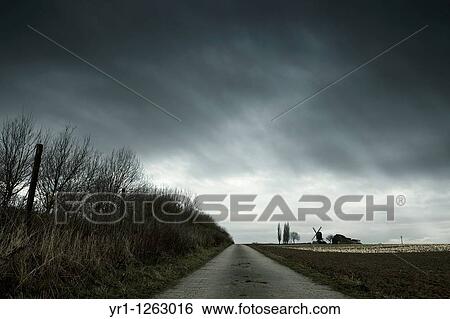 Stock Photograph - Landscape with an old windmill during winter. Dramatic sky. Shot in North Rhine-Westphalia, Germany.. Fotosearch