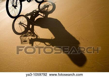 Stock Image - Laos, Si Phan Don Four Thousand Islands, Don Khon Female tourist on a hired bicycle on a sandy beach on the island of Don Knon. Fotosearch