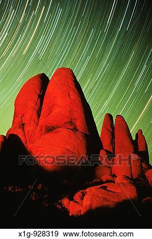 Stock Photo - Large granite rocks lit by campfire with star trails whirling in the background at Joshua Tree National Park, California, USA. Fotosearch