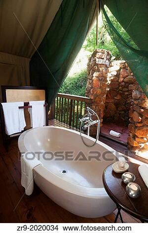 Picture - Large oval bathtub inside a luxury safari tent, Botlierskop Game Lodge, Mosselbay, South Africa.. Fotosearch