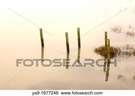 Stock Photograph - Late evening light on a small wooden bridge covered by flood waters. Fotosearch