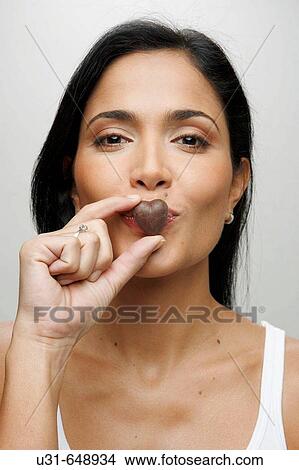 Latin girl blowing a kiss with a valentine's chocolate heart View Large Photo Image Picture - Latin girl blowing a kiss with a valentine's chocolate heart. Fotosearch