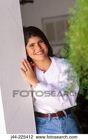 Stock Image - Latin girl leaning on column smiling. Fotosearch