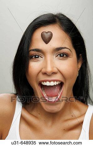 Latin girl looking surprised at the camera with a valentine's chocolate heart on her forehead View Large Photo Image Stock Photography - Latin girl looking surprised at the camera with a valentine's chocolate heart on her forehead. Fotosearch