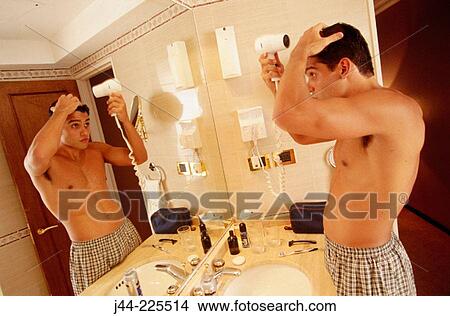 Latin man blowing his hair in a hotel room bathroom View Large Photo Image Picture - Latin man blowing his hair in a hotel room bathroom. Fotosearch