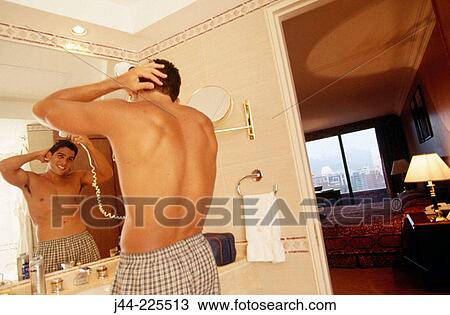 Latin man blowing his hair in a hotel room bathroom View Large Photo Image Stock Image - Latin man blowing his hair in a hotel room bathroom. Fotosearch
