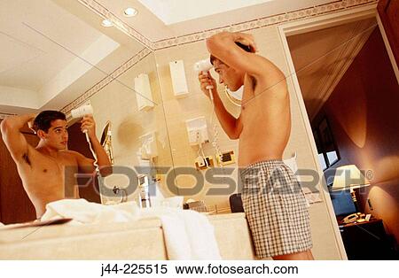 Latin man blowing his hair in a hotel room bathroom View Large Photo Image Stock Photography - Latin man blowing his hair in a hotel room bathroom. Fotosearch
