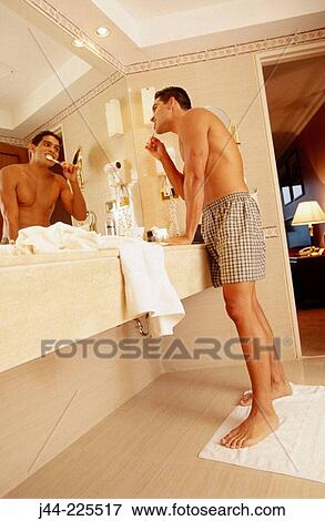Latin man brushing his teeth in a hotel room bathroom View Large Photo Image Stock Photo - Latin man brushing his teeth in a hotel room bathroom. Fotosearch