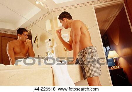 Latin man brushing his teeth in a hotel room bathroom View Large Photo Image Stock Photo - Latin man brushing his teeth in a hotel room bathroom. Fotosearch