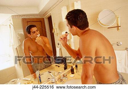 Latin man brushing his teeth in a hotel room bathroom View Large Photo Image Stock Photograph - Latin man brushing his teeth in a hotel room bathroom. Fotosearch