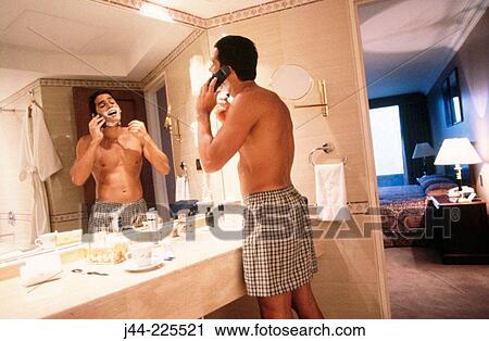 Latin man shaving while talking on cell phone in a hotel bathroom View Large Photo Image Stock Image - Latin man shaving while talking on cell phone in a hotel bathroom. Fotosearch
