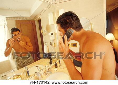Latin man shaving while talking on cellular in a hotel bathroom View Large Photo Image Stock Image - Latin man shaving while talking on cellular in a hotel bathroom. Fotosearch