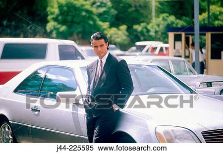 Latin man with suit standing by sport car in parking lot View Large Photo Image Stock Photography - Latin man with suit standing by sport car in parking lot. Fotosearch
