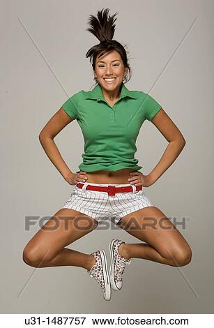 Stock Photo - Latin woman jumping happily in a studio setting. Fotosearch