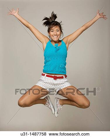 Latin woman jumping happily in a studio setting View Large Photo Image Stock Photo - Latin woman jumping happily in a studio setting. Fotosearch