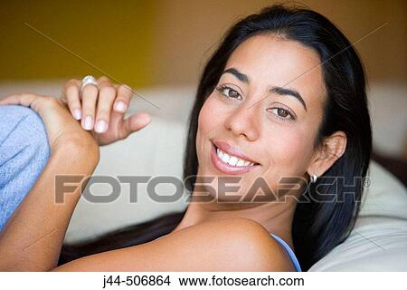 Latin woman sitting on couch smiling View Large Photo Image Picture - Latin woman sitting on couch smiling. Fotosearch