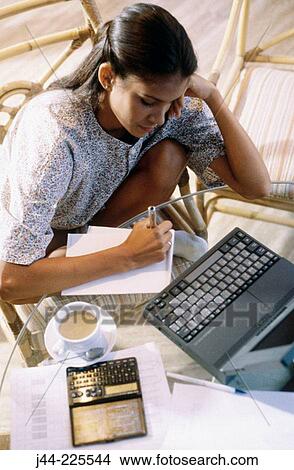 Picture - Latin woman working with laptop computer and cup of coffee in the house terrace. Fotosearch