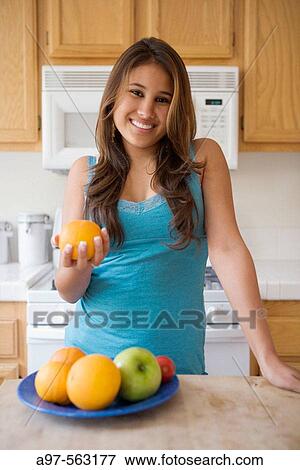 Latina teen girl in blue tank top holding an orange. View Large Photo Image Stock Photo - Latina teen girl in blue tank top holding an orange.. Fotosearch