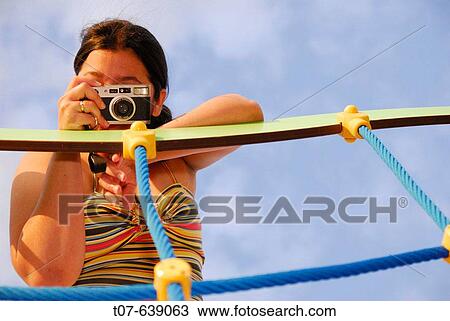 Stock Image - Latino Woman holding a camera.. Fotosearch